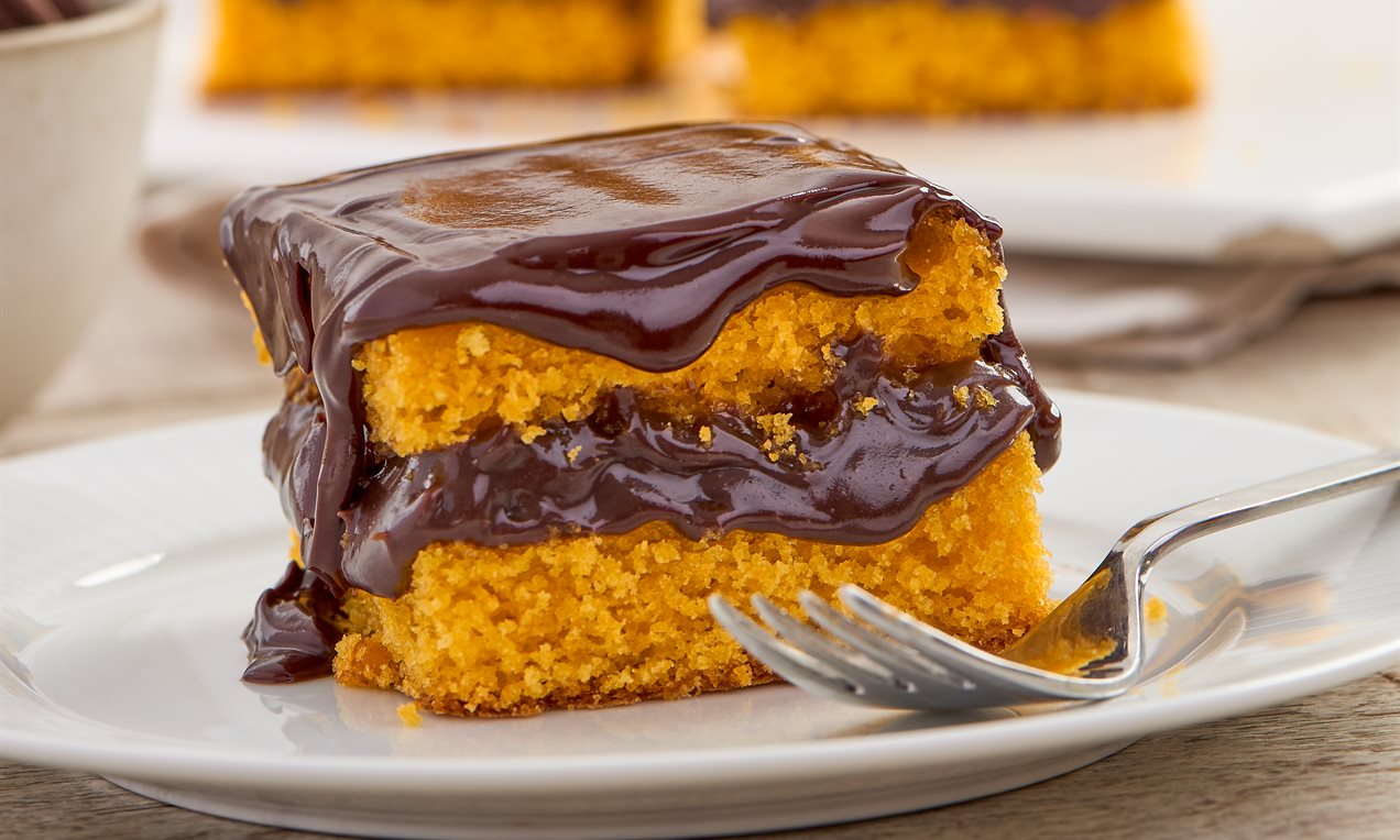 Bolo de cenoura fofinho coberto com calda de chocolate brilhante.
